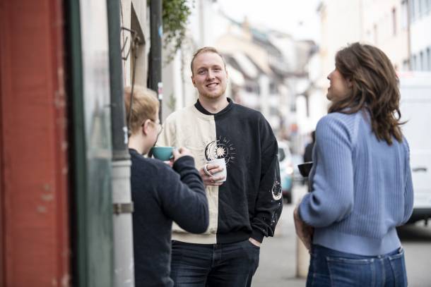 Alessandro, Sophia und Kajetan trinken Kaffee vor dem Büro