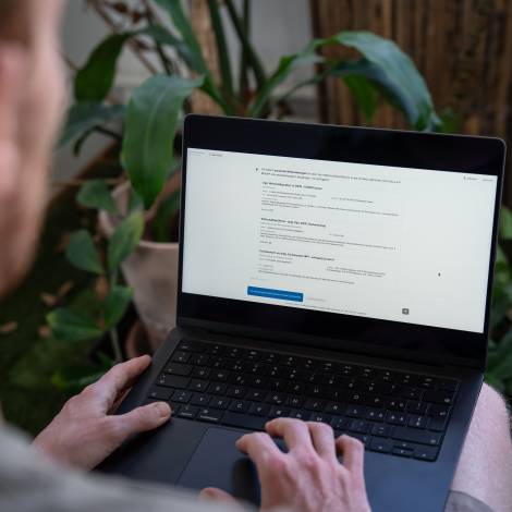 Eine Person von hinten über die Schulter fotografiert, die an einem Laptop arbeitet und die Co-Pilot-Benutzeroberfläche geöffnet hat.