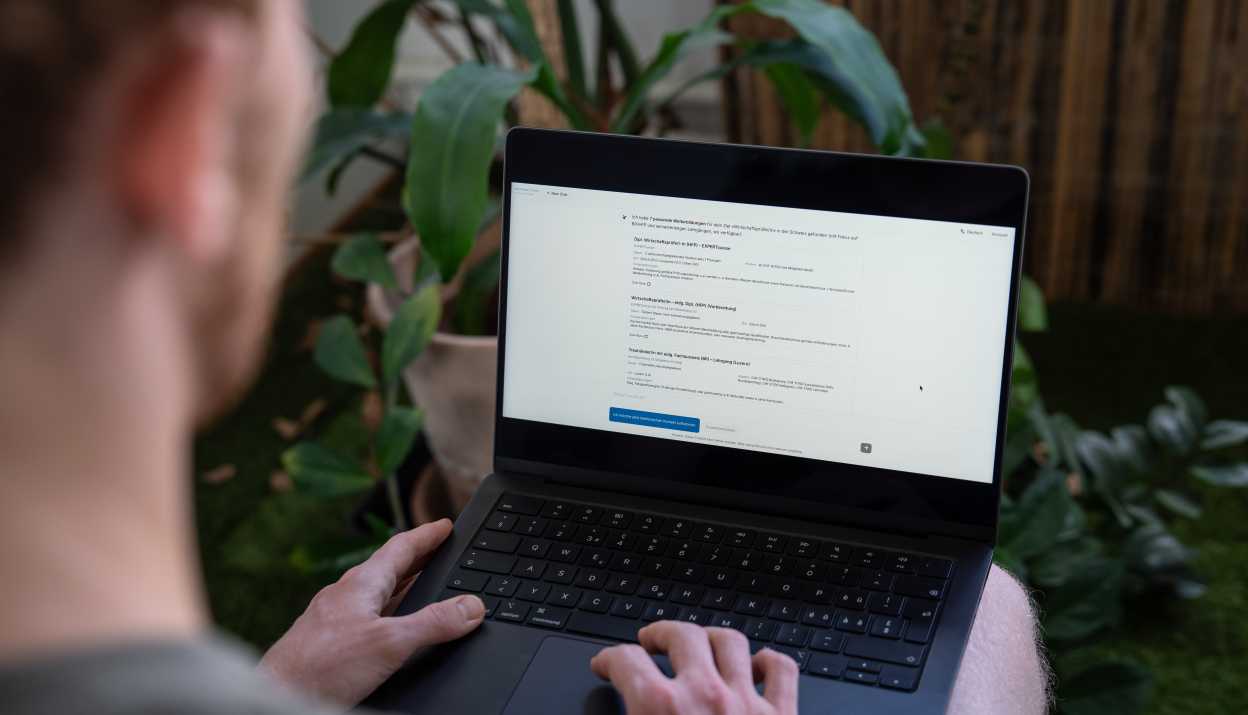 Eine Person von hinten über die Schulter fotografiert, die an einem Laptop arbeitet und die Co-Pilot-Benutzeroberfläche geöffnet hat.