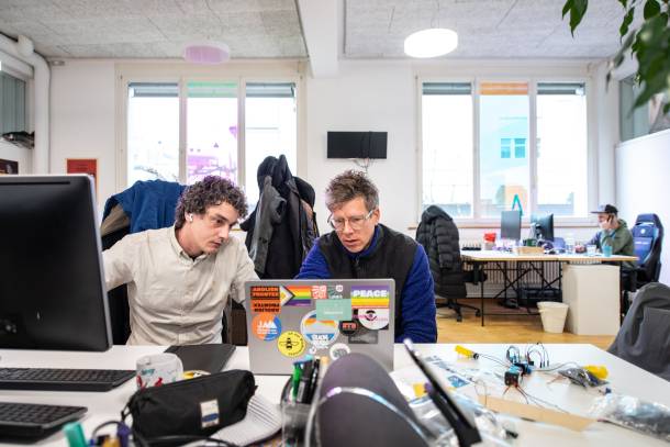 Corsin und Adrian schauen gemeinsam auf einen Laptop