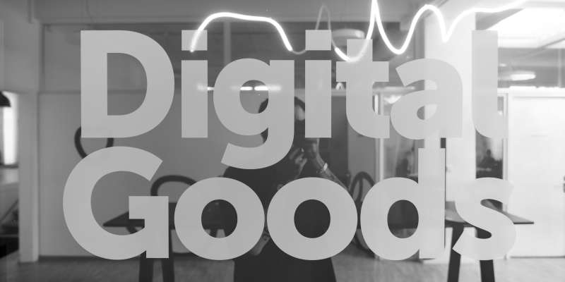 Schriftzug "Digital Goods" fotografiert vor einem farbig spiegelnden Fenster