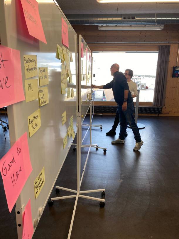 Workshop Einblick mit Post-its auf Whiteboards und Diskussion zwischen zwei Personen