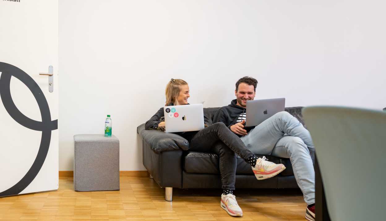 Fabienne und Martin mit Laptops auf dem Sofa