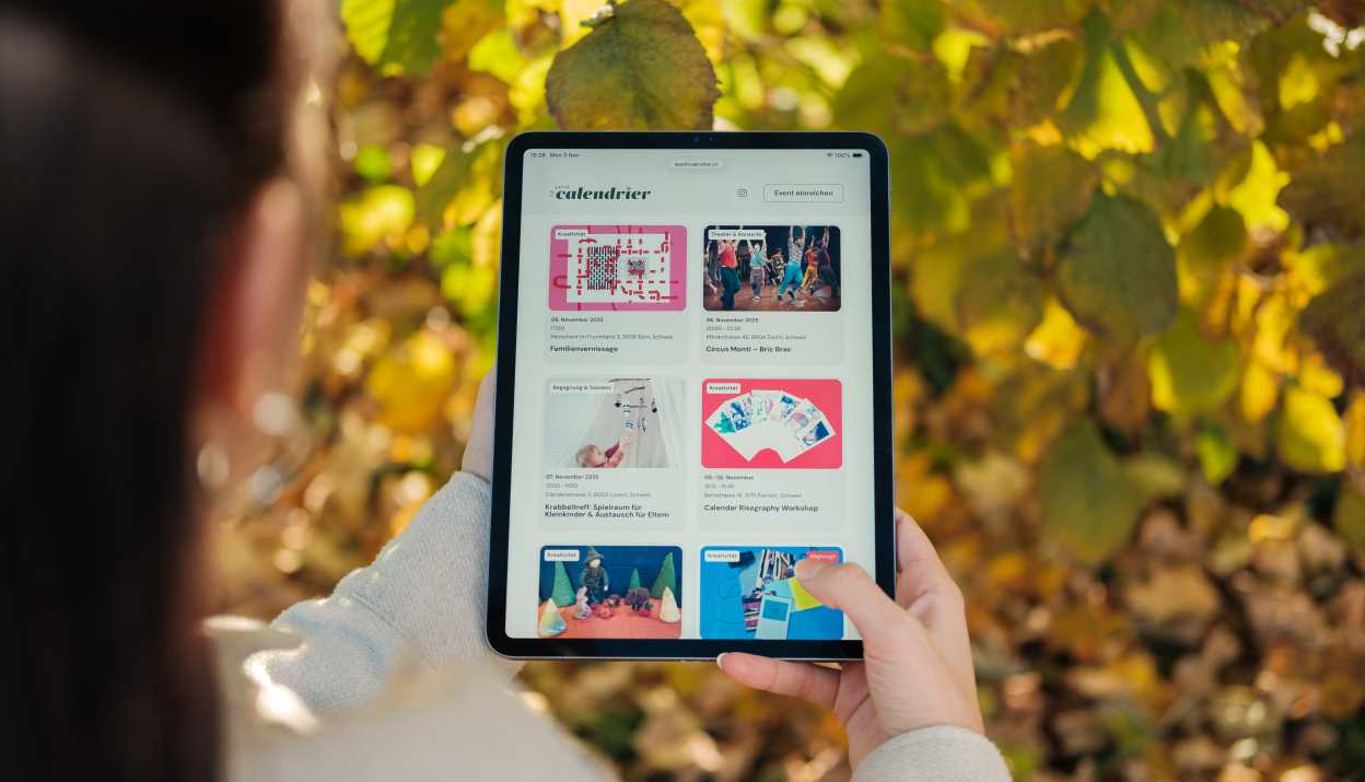 Le petit calendrier wird auf einem Tablet angeschaut, im Hintergrund sind Blätter eines Baumes