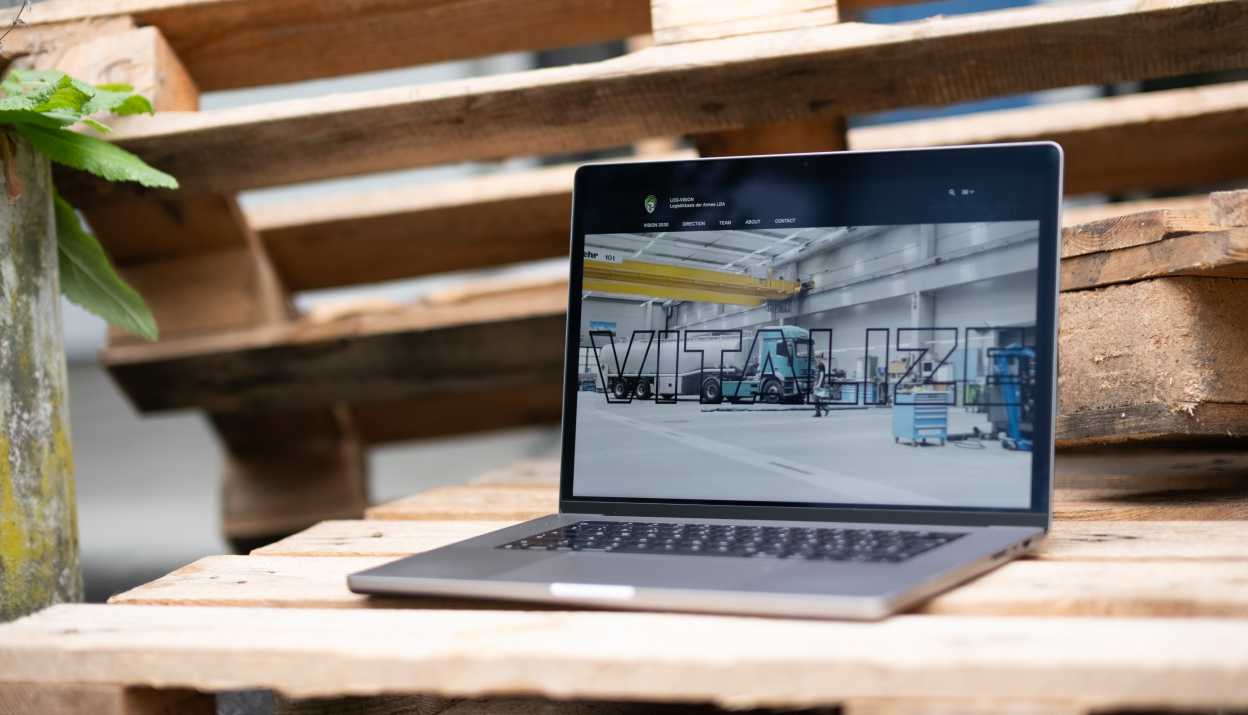 LOG-VISION Website geöffnet auf einem MacBook das auf Euro Palette steht