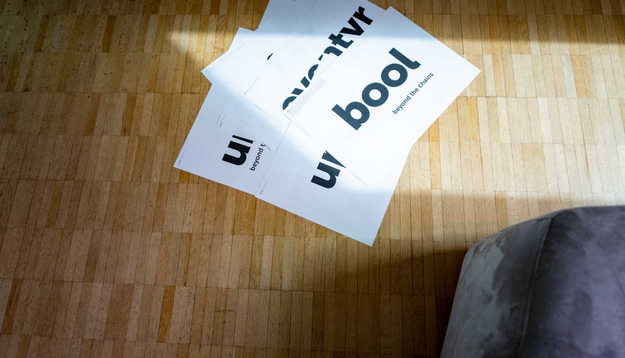 Weisse A3 Blätter mit verschiedenen Markennamen und Claims liegen auf einem Parkettboden