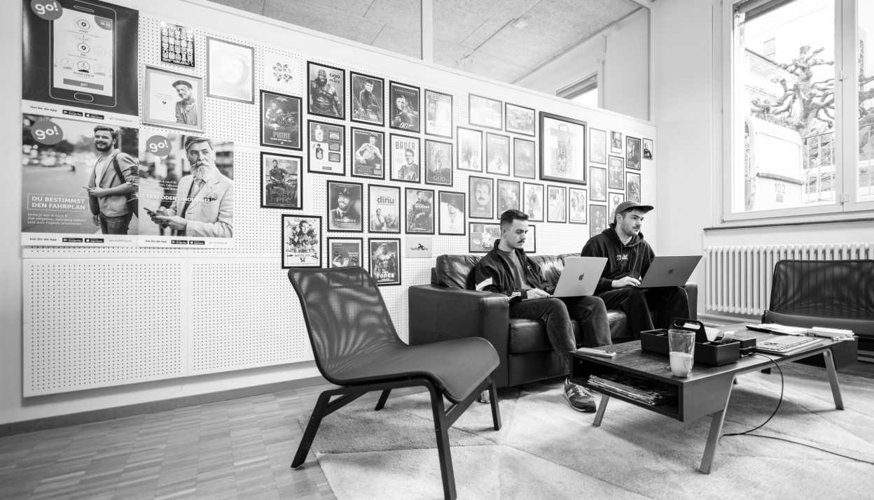 Nick und Aaron sitzen auf dem Sofa im Apps with love Wohnzimmer mit je einem MacBook auf dem Schoss