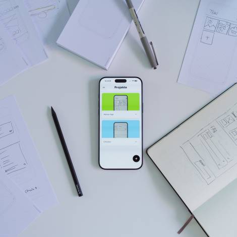 iPhone, darauf geöffnet die Prototyper App. Daneben liegen Skizzen und Stifte