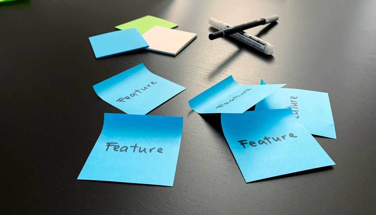 Blaue Post-its auf denen "Feature" steht kleben auf einem Tisch
